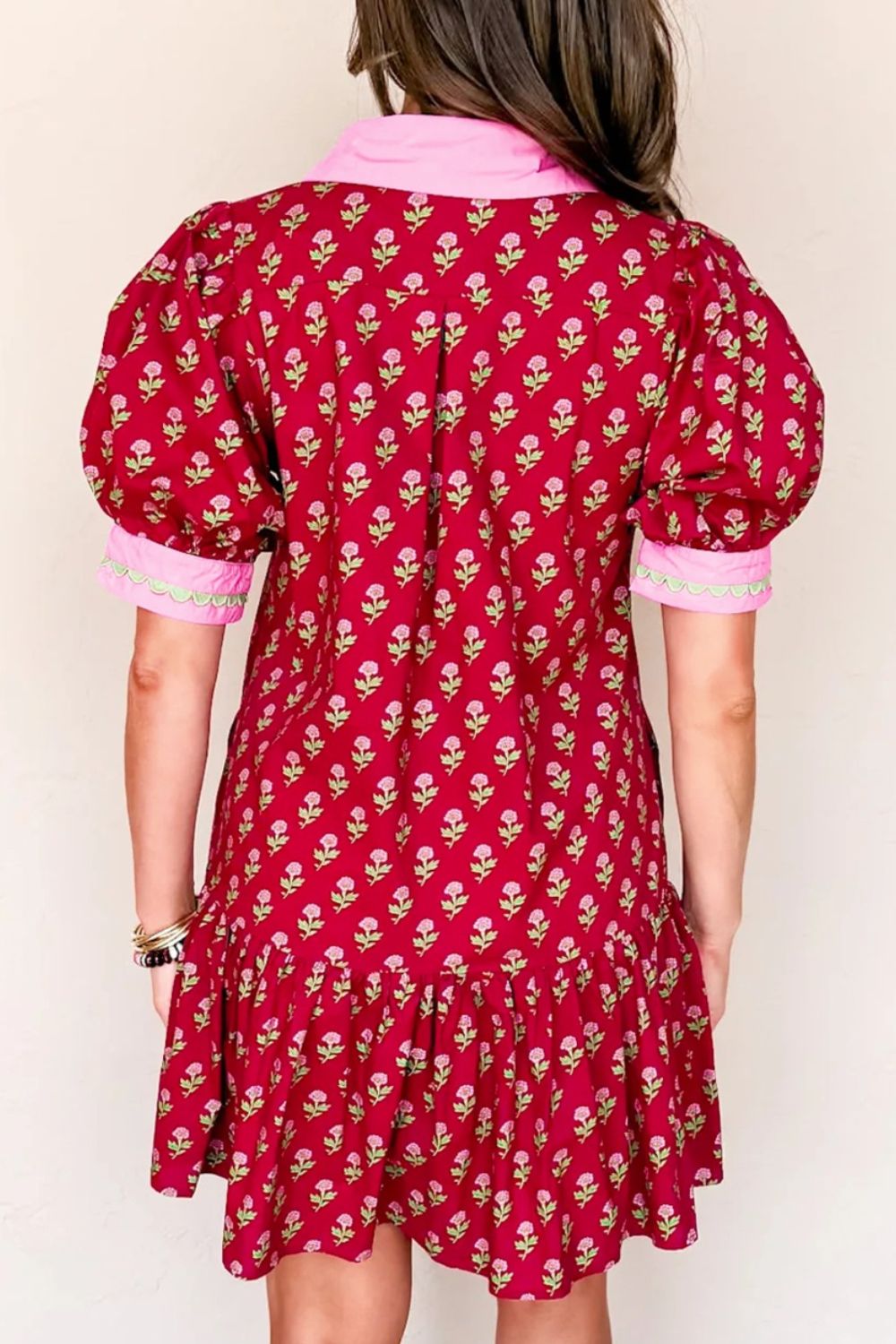 Red floral dress with pink trim worn by a person on a white background