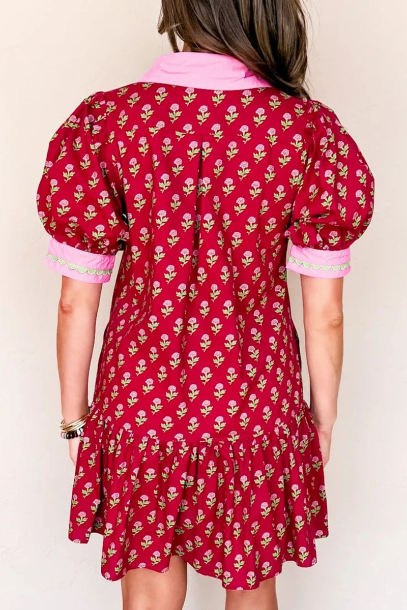 Red floral dress with pink trim worn by a person on a white background