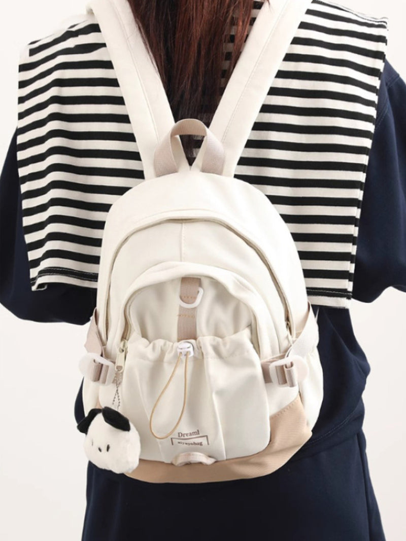 White backpack with a small plush toy attached, worn by a person in a striped shirt.