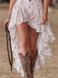 Person wearing a white floral dress with ruffles and brown cowboy boots on a blurred background
