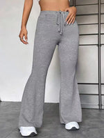Person wearing gray flared pants with a white background