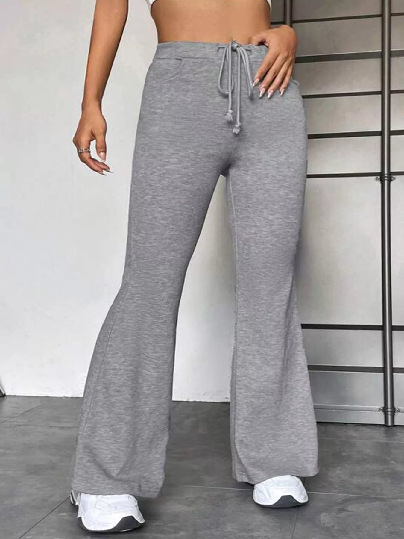 Person wearing gray flared pants with a white background
