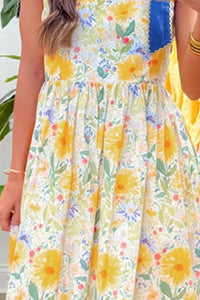 Person wearing a floral dress with yellow flowers and green leaves.