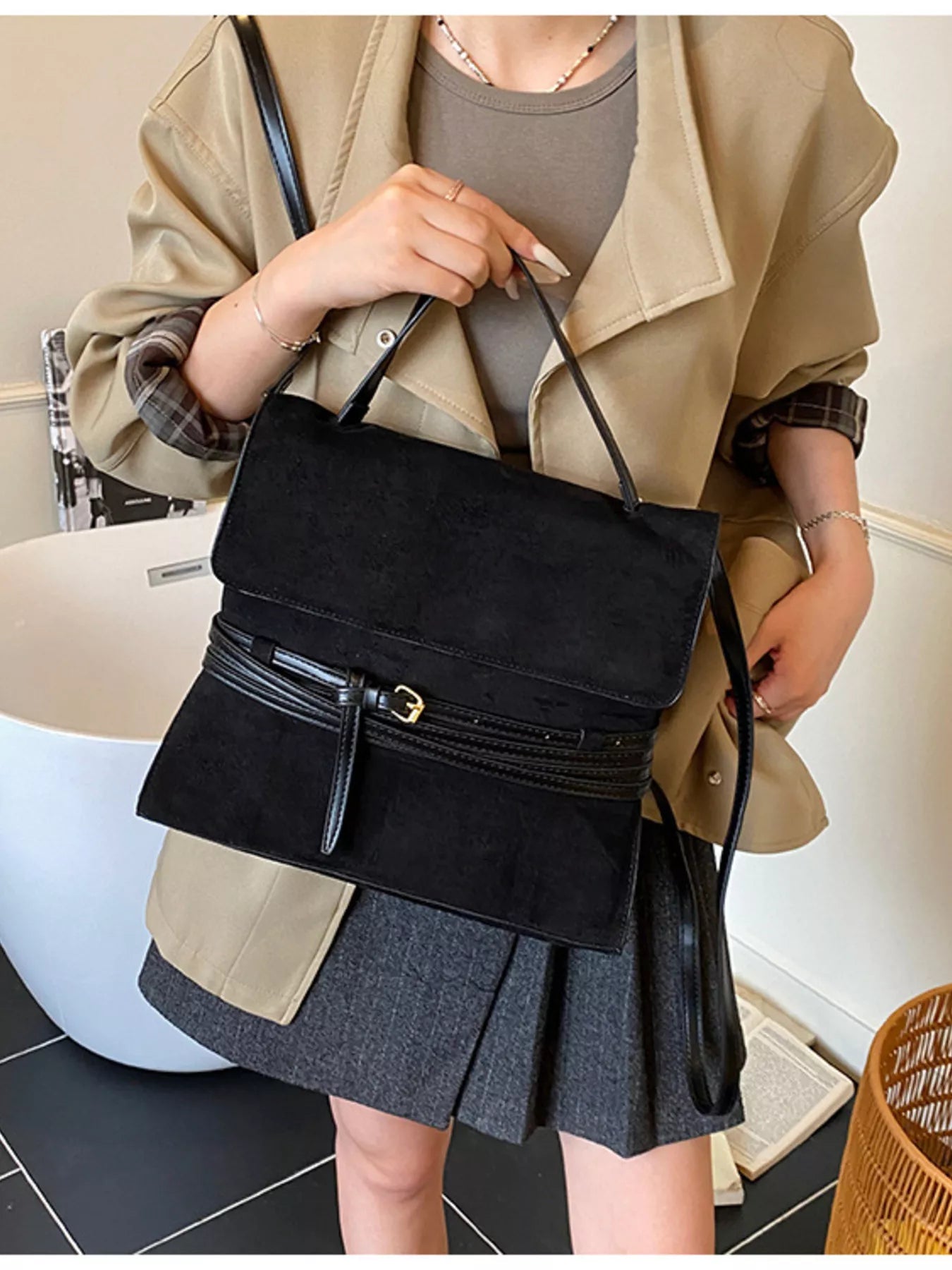 Person holding a black handbag in an indoor setting