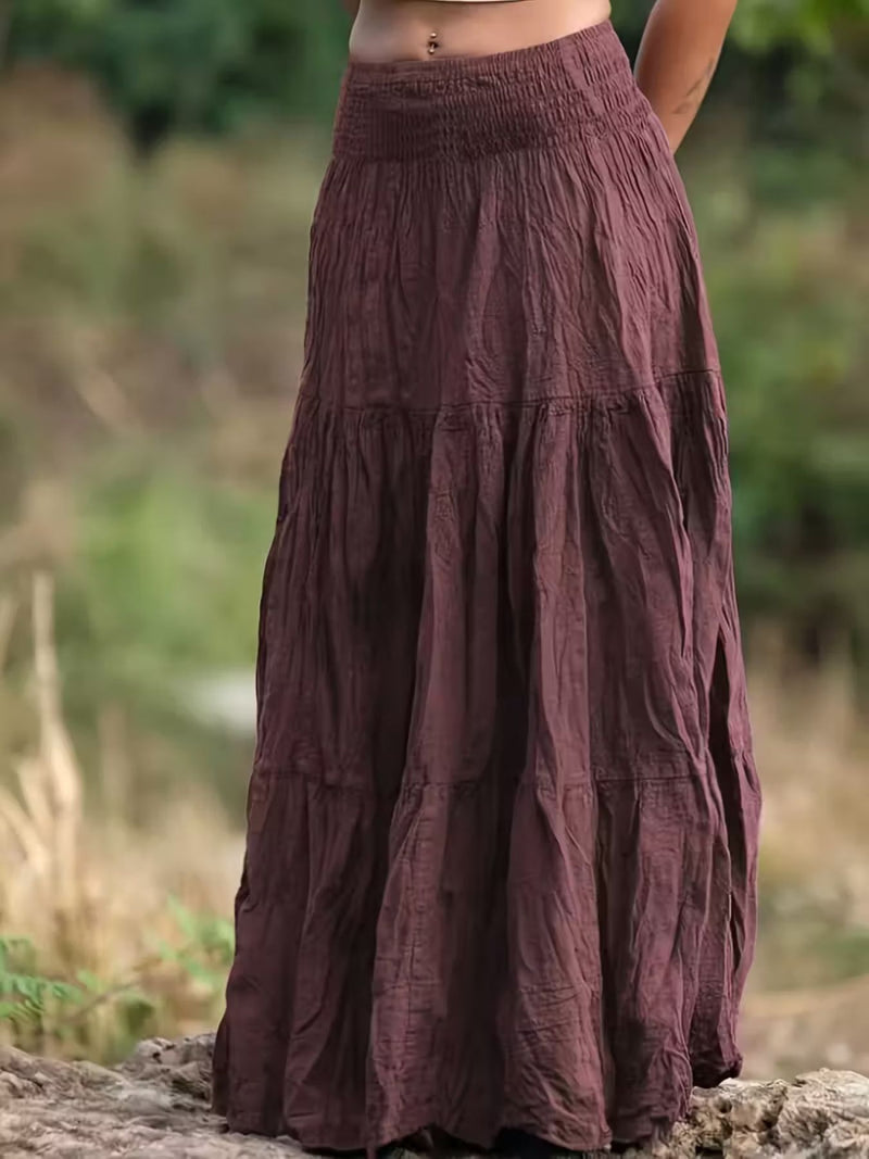Long brown skirt worn by a person standing outdoors with a blurred natural background