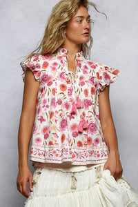 Woman wearing a floral blouse with ruffled sleeves against a plain background