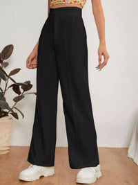 Person wearing black wide-leg pants with a white background