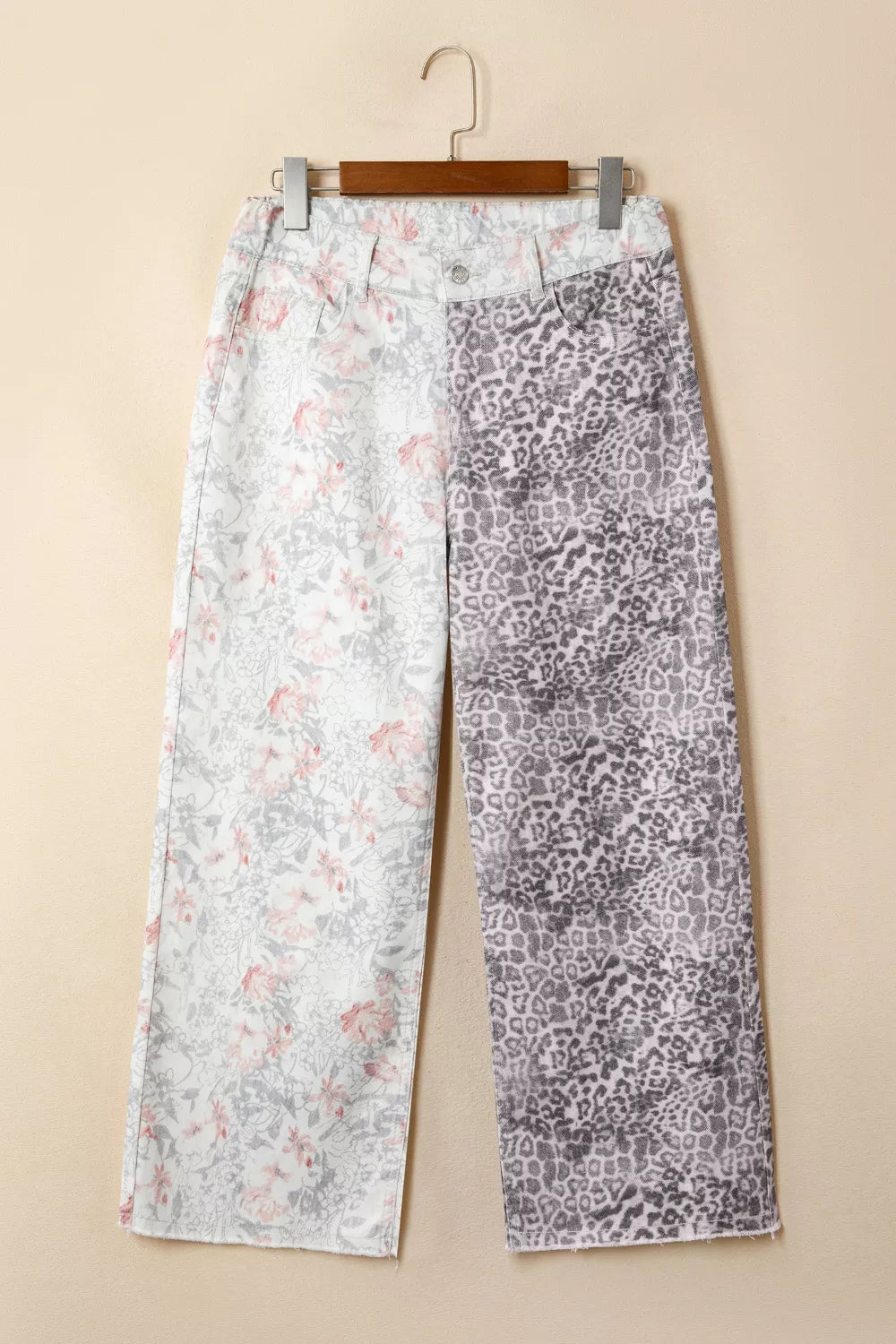 Two pairs of pants with different patterns hanging on a beige wall.