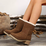 Brown suede boots with white fur lining worn by a person sitting on wooden logs.