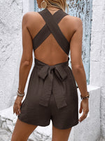 Brown romper with open back worn by a person against a textured white wall.
