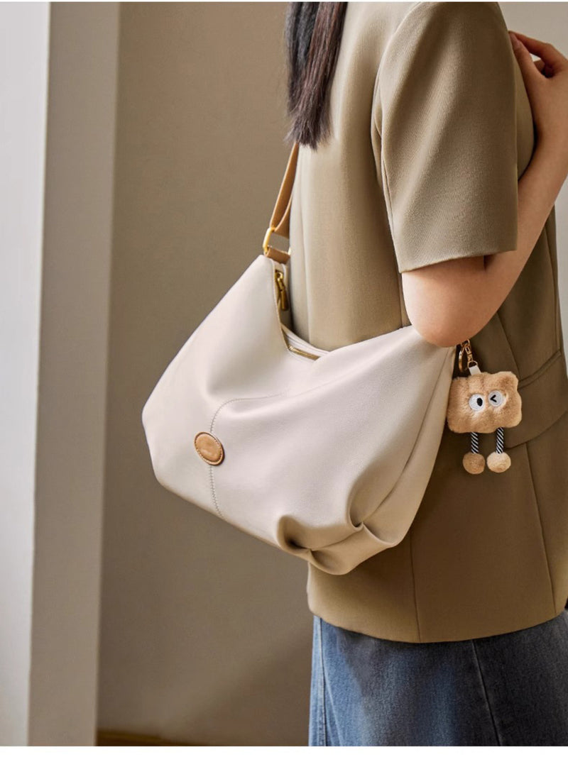 Person holding a white handbag with a bear charm against a neutral background