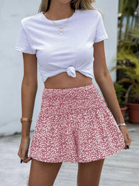 Person wearing a white tied crop top and pink floral shorts outdoors.