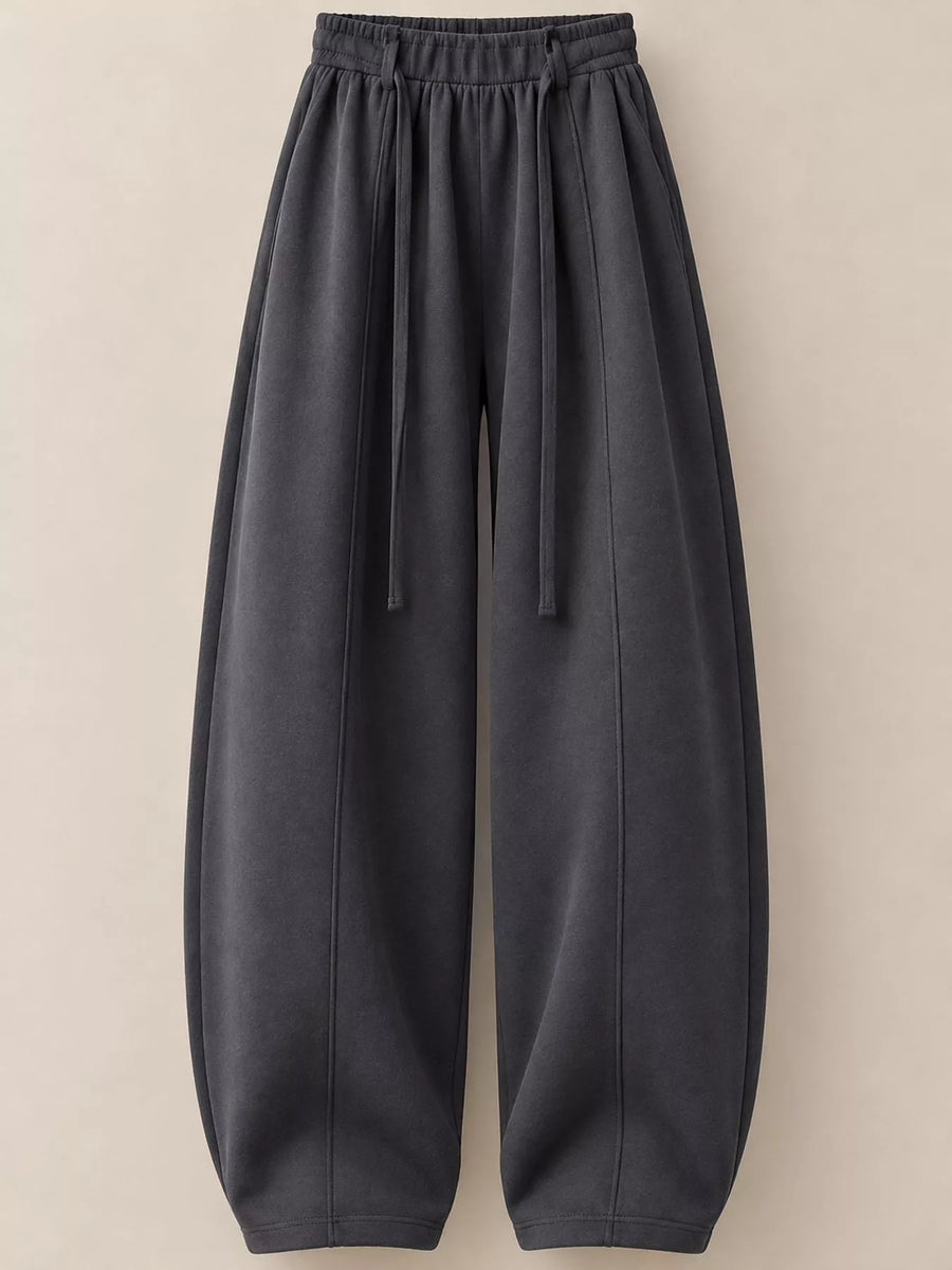 Dark gray wide-leg lounge pants with an elastic drawstring waist and tapered legs, shown against a solid beige background.