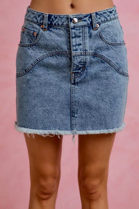 Blue denim skirt worn by a person on a pink background