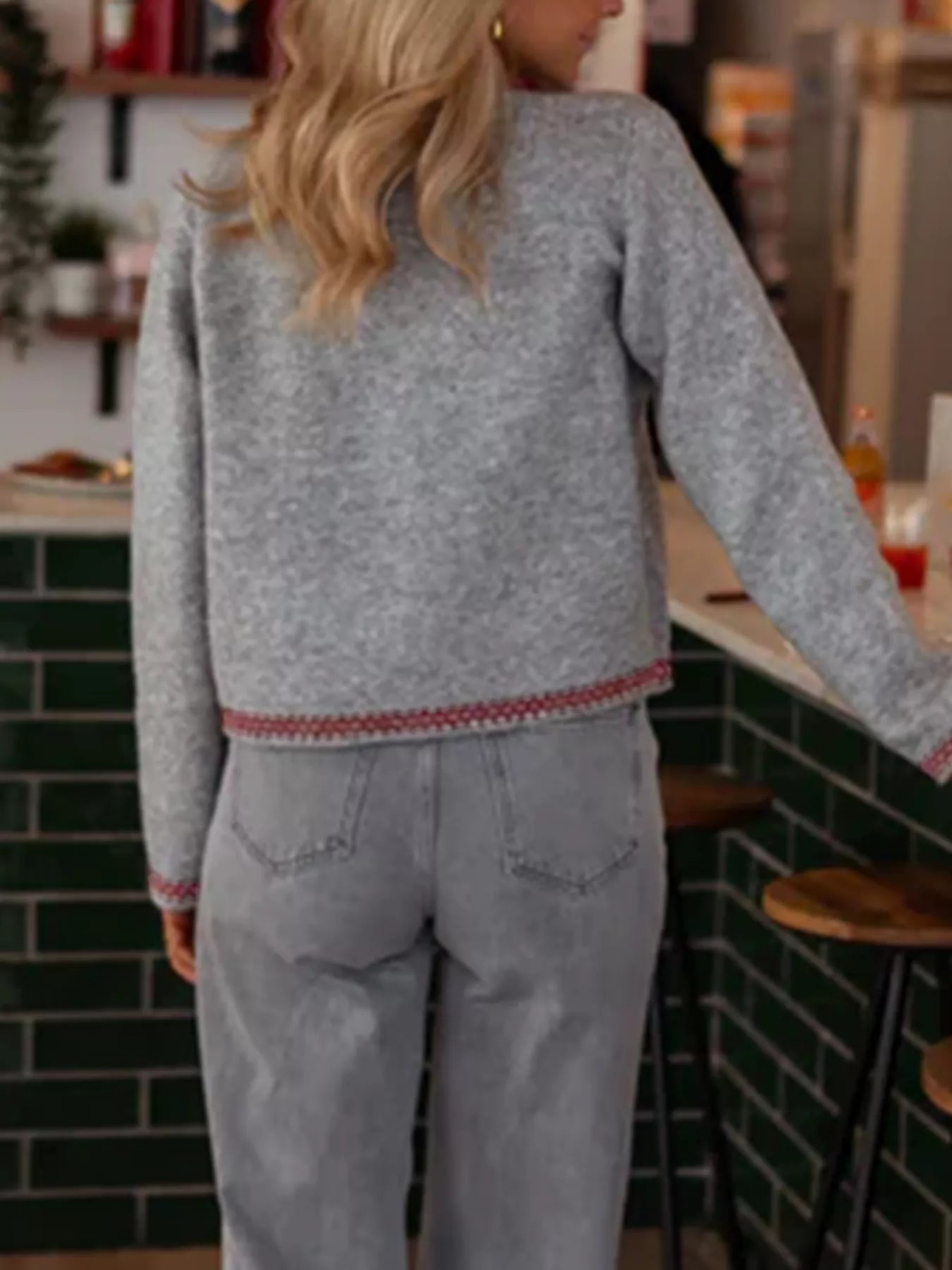 Person wearing a gray sweater with red trim in a kitchen setting