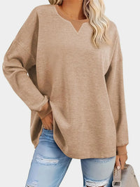 Person wearing a beige sweater and light blue jeans on a white background