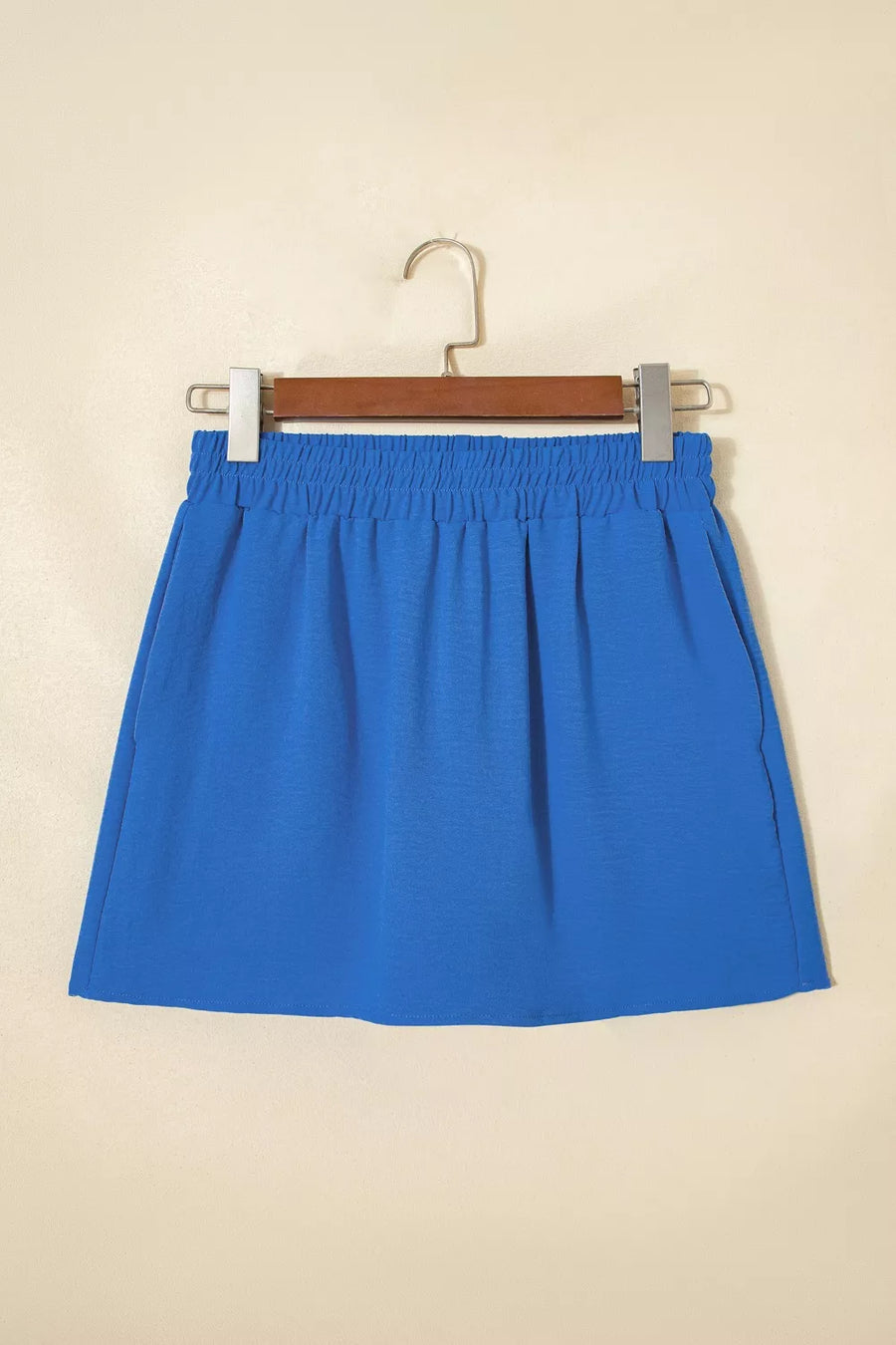 Blue skirt on a hanger against a beige background