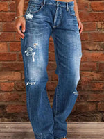Person wearing distressed blue jeans standing against a brick wall.