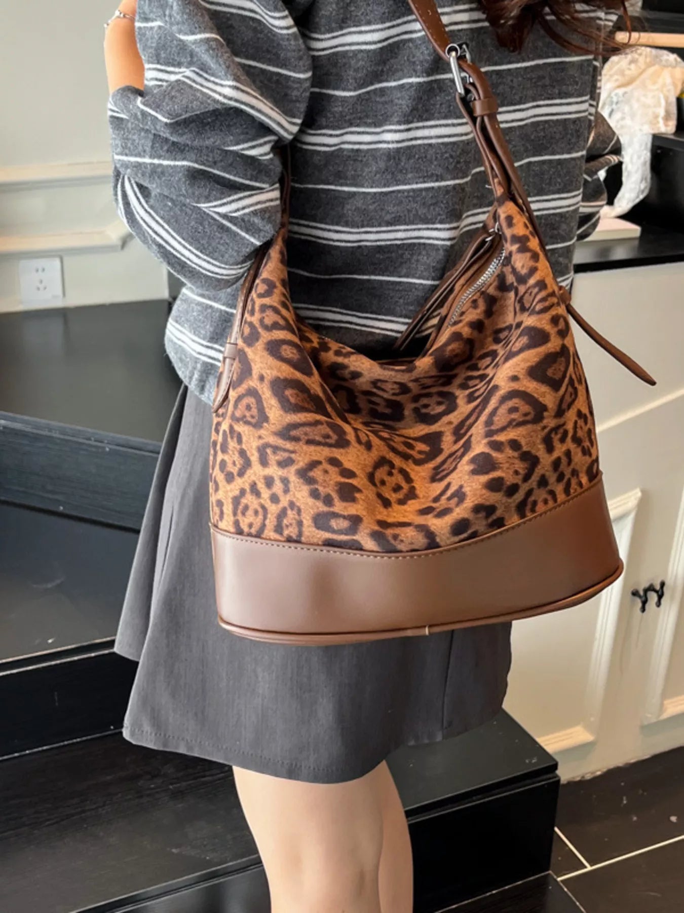 Person wearing a leopard print handbag in an indoor setting