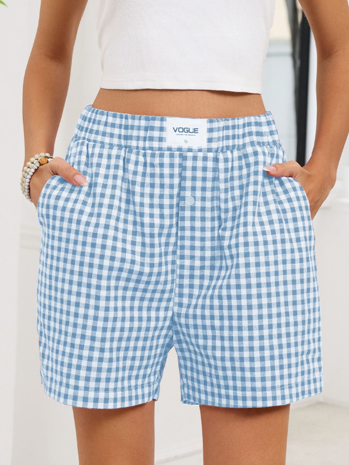 Blue and white checkered shorts with 'Vogue' branding worn by a person.