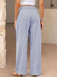 Person wearing blue and white checkered pants in a neutral setting