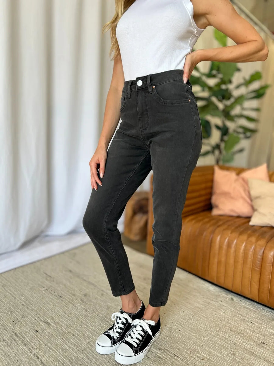 Person wearing black pants and white sneakers in a living room setting