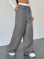 Person wearing gray striped wide-leg pants on a plain background