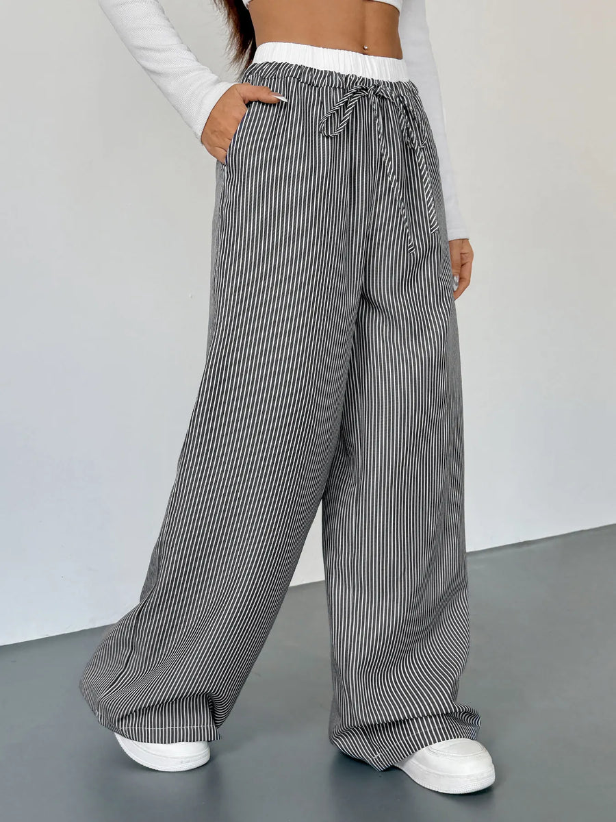 Person wearing gray striped wide-leg pants on a plain background
