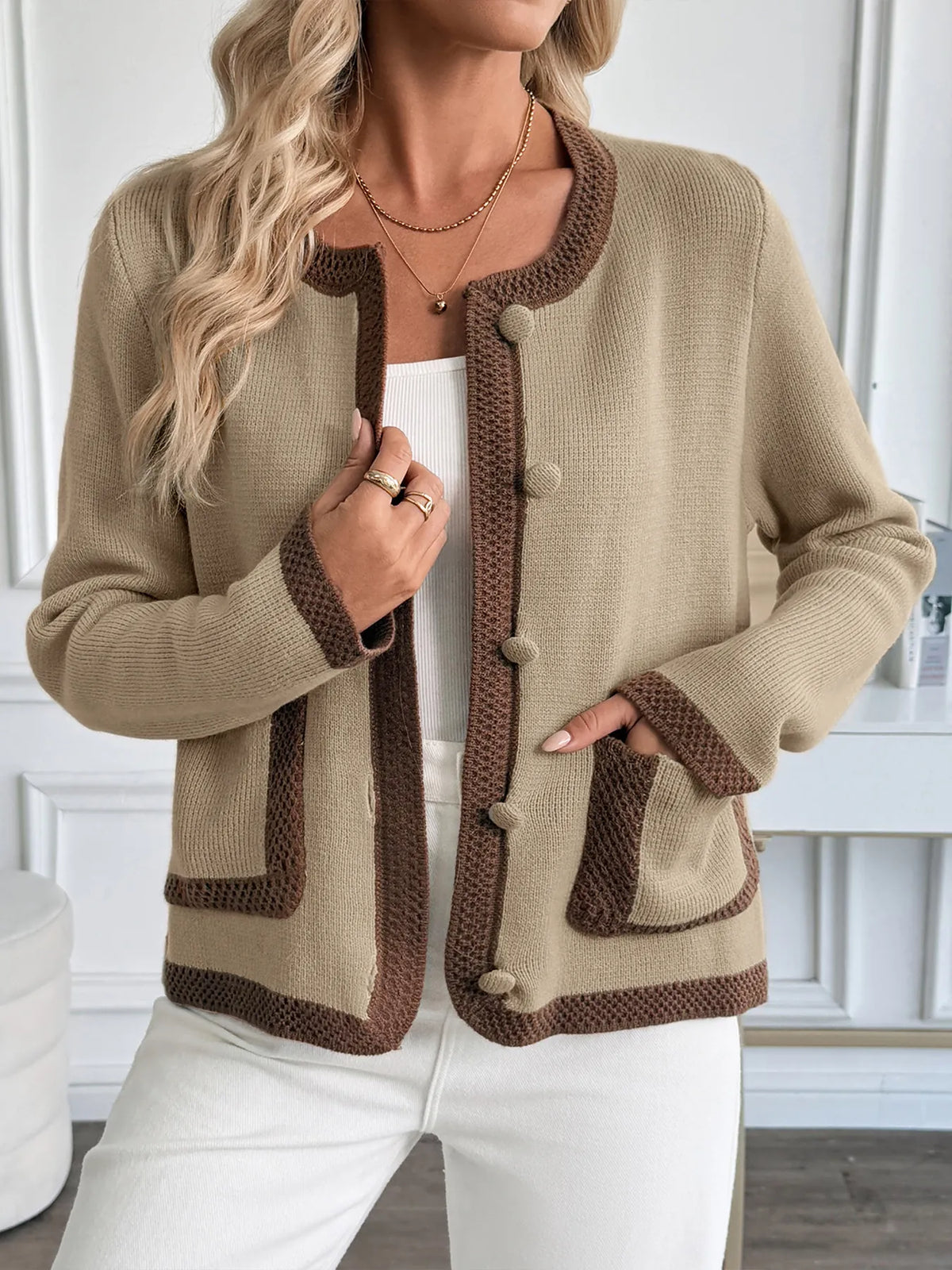 Woman wearing a beige and brown cardigan with a white background