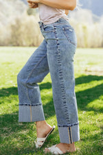 Person wearing blue jeans standing on grass with a blurred background
