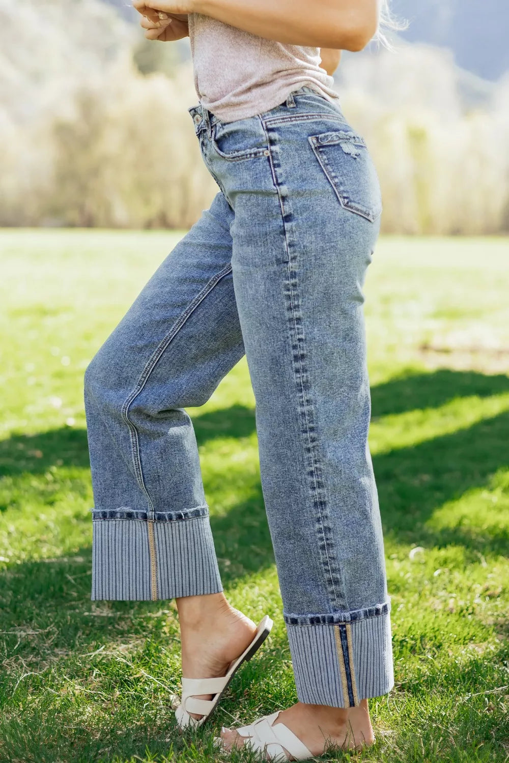 Person wearing blue jeans standing on grass with a blurred background