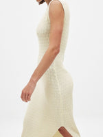 Close-up of a person wearing a cream ribbed knit dress on a white background