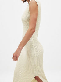 Close-up of a person wearing a cream ribbed knit dress on a white background