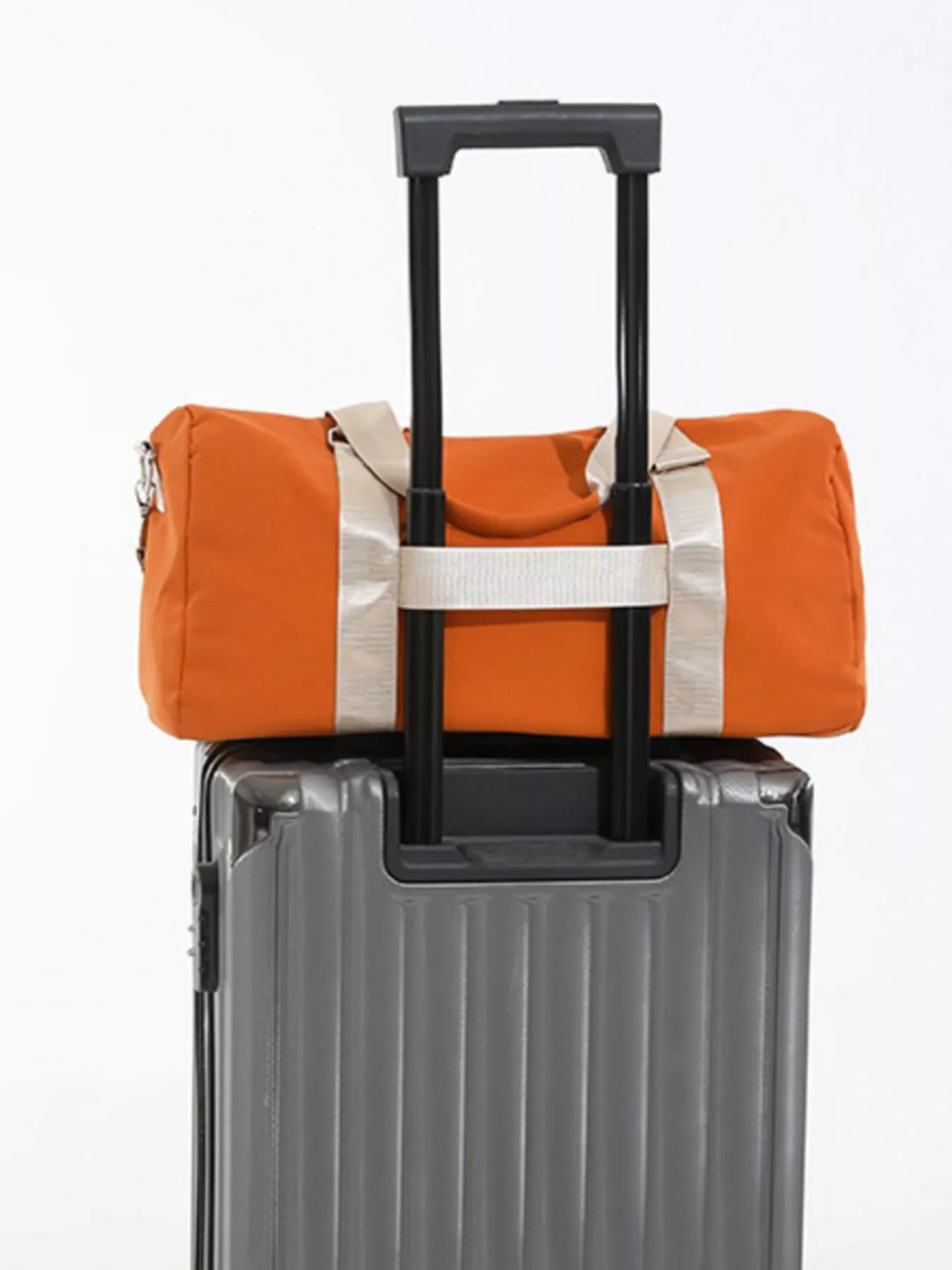 Orange duffel bag with white trim attached to a gray suitcase on a white background
