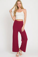 Woman wearing a white top and burgundy pants on a white background
