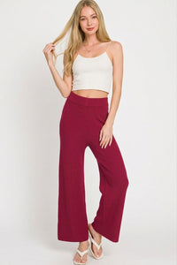 Woman wearing a white top and burgundy pants on a white background