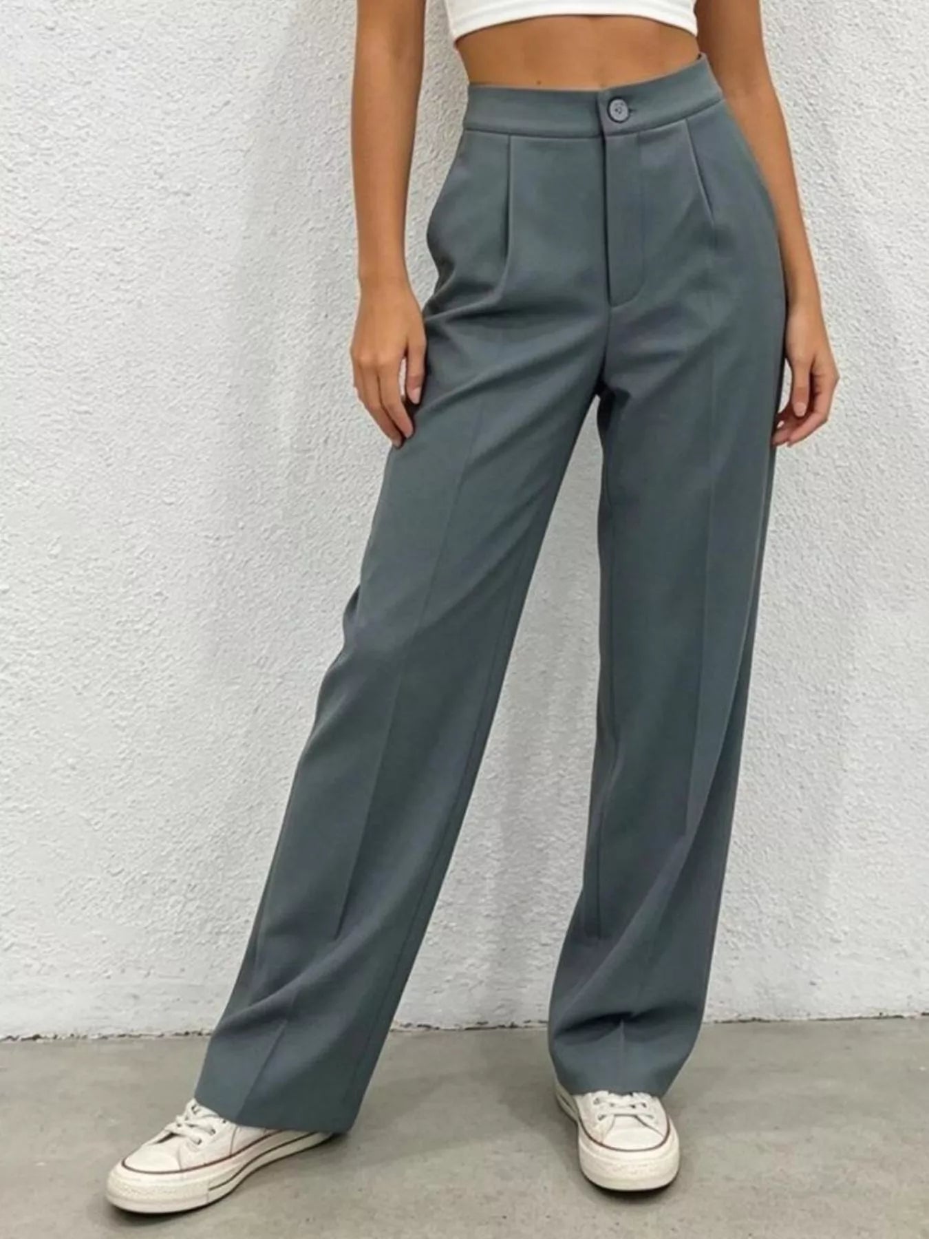 Person wearing gray wide-leg pants against a white wall