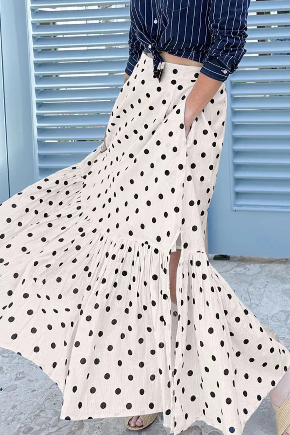 Person wearing a white polka dot skirt with a blue background