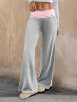Person wearing gray flared pants with a pink waistband against a beige wall.