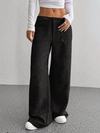Person wearing black wide-leg pants with a plain background