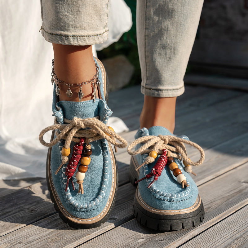 Blue suede shoes with decorative elements on a wooden floor