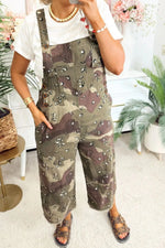Person wearing camouflage overalls in a home setting with plants and furniture.
