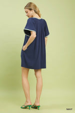 Woman wearing a navy dress with white trim on a light green background