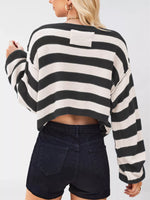Person wearing a black and white striped sweater with a plain background
