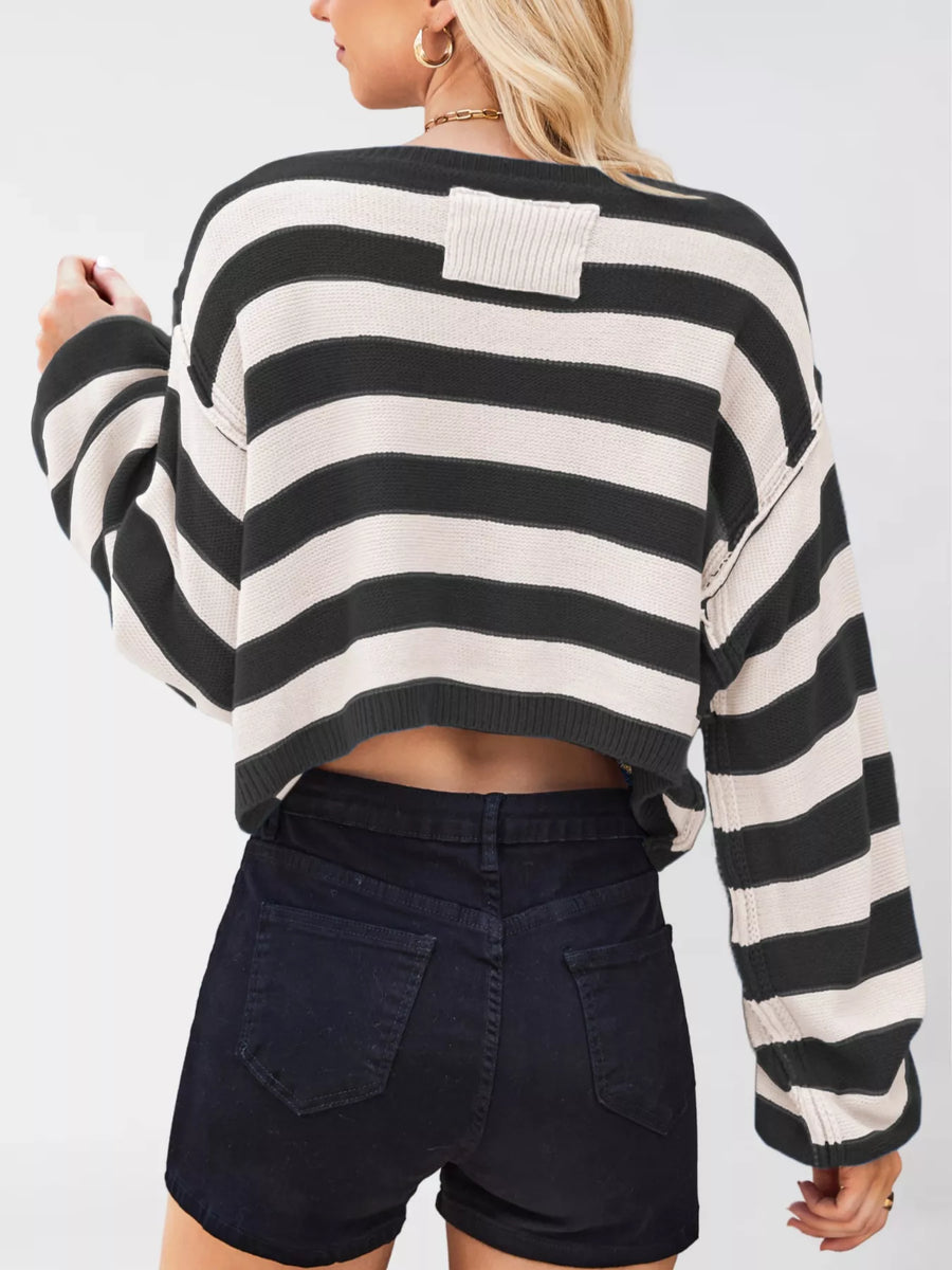 Person wearing a black and white striped sweater with a plain background