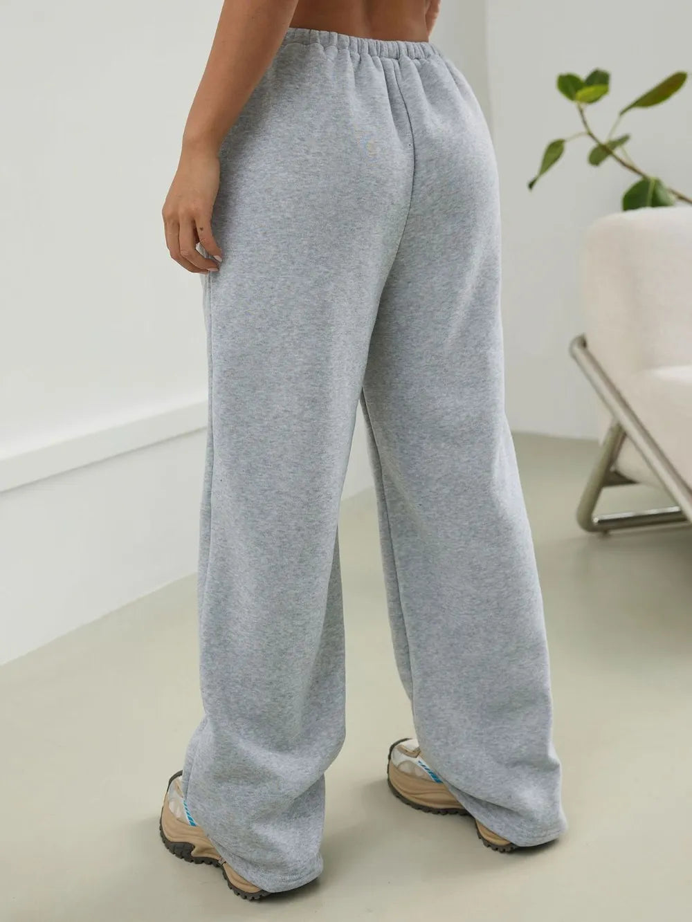 Person wearing gray sweatpants in a minimal indoor setting