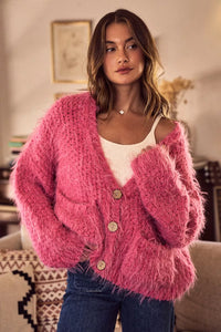 Woman wearing a pink fuzzy cardigan in a cozy indoor setting