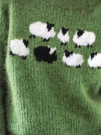 Green knitted fabric with black and white sheep pattern