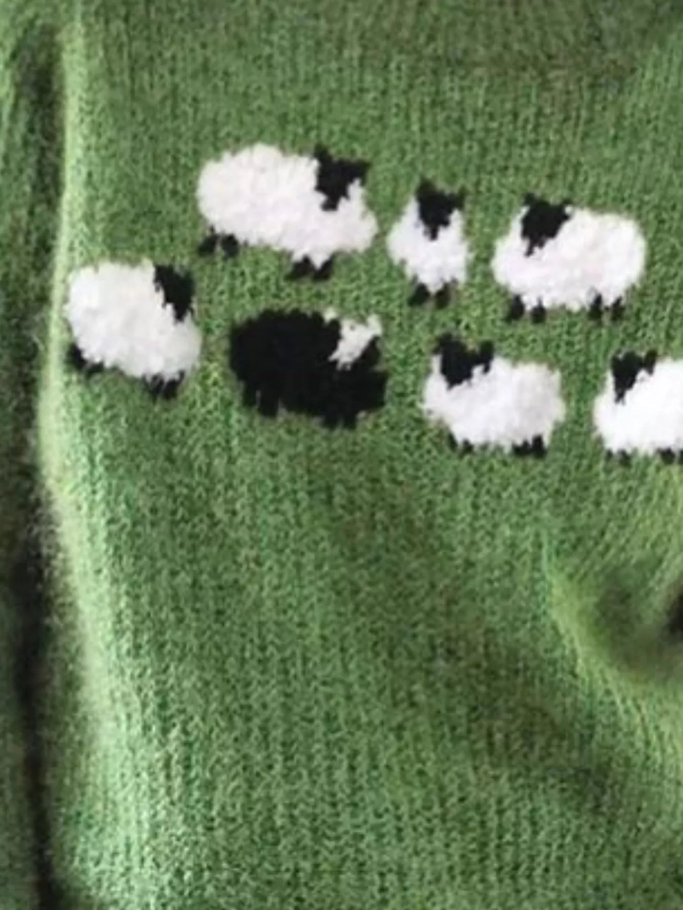 Green knitted fabric with black and white sheep pattern