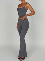 Woman wearing a gray sleeveless top and flared pants on a plain background